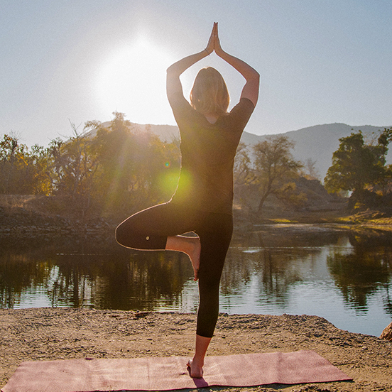 A lady practicing Yoga at sunrise